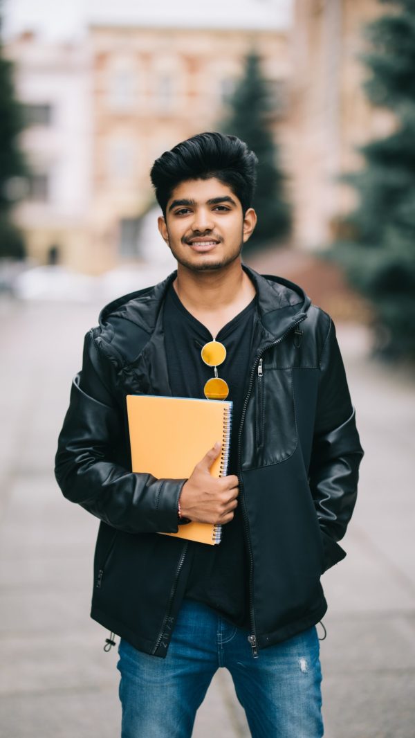 handsome-young-indian-student-man-holding-notebooks-while-standing-street (1)